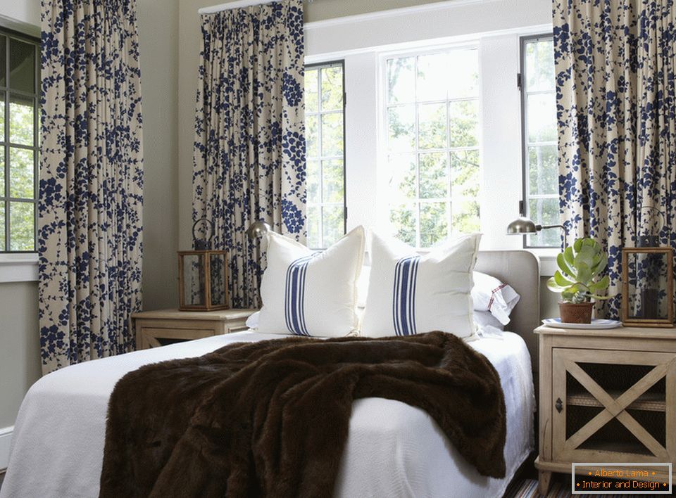 Flores azules en las cortinas y rayas en las almohadas se combinan armoniosamente en el interior del dormitorio