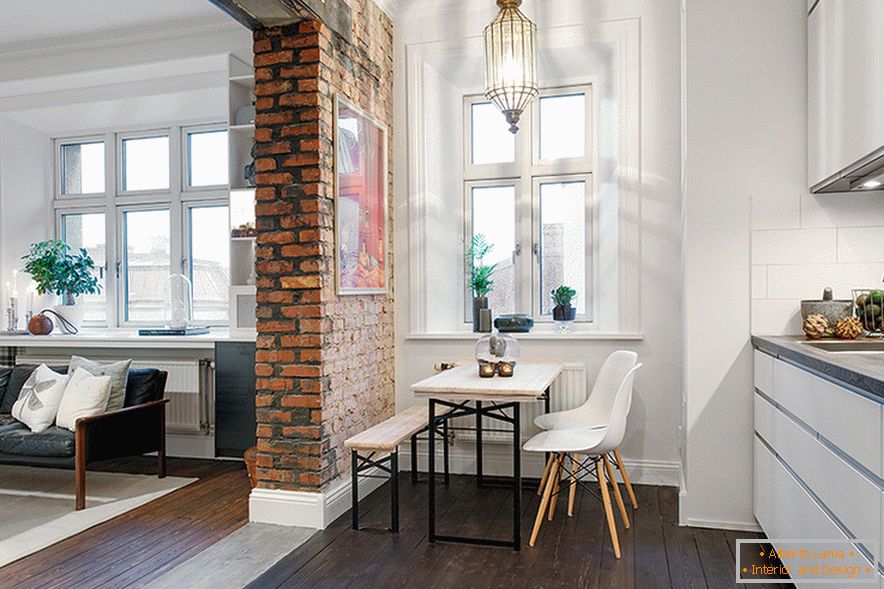 Un arco de ladrillo sin pulir zonal divide el espacio en una sala de estar y una cocina