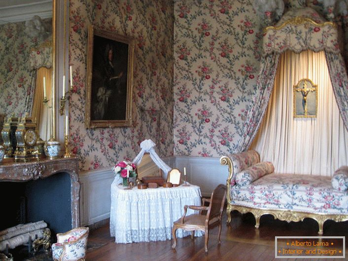 La decoración colorida de las paredes está en armonía con la tapicería del sofá y el toldo sobre ella. Un salón barroco con una gran chimenea es una gran idea para una casa de campo.