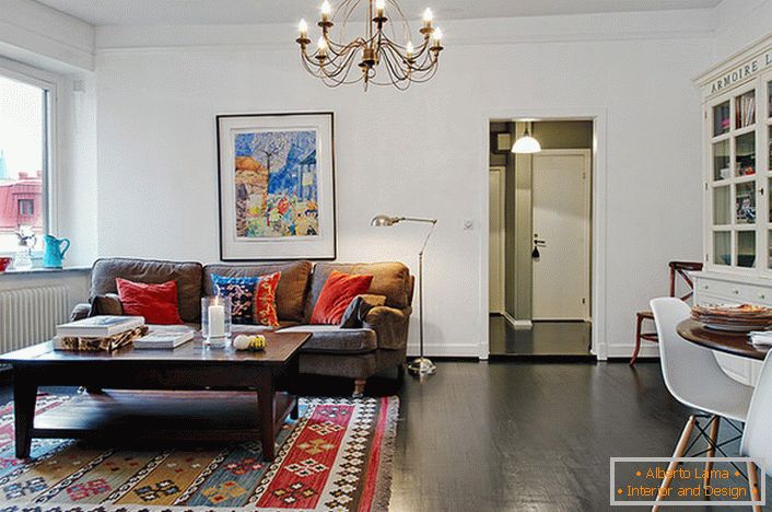 Una elegante habitación en un apartamento típico de la ciudad está decorada con almohadas brillantes en el sofá y la alfombra. 