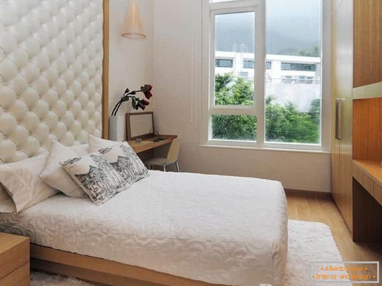 Una cama pequeña con un cabecero de cuero y en el dormitorio con una ventana grande