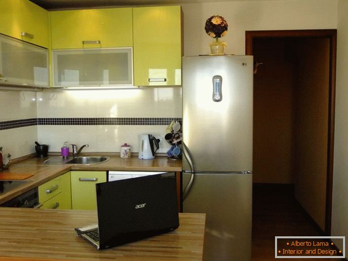 Elegante área de cocina de 12 metros cuadrados de color oliva tierna. El espacio de la cocina está organizado de una manera práctica y funcional.