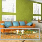 Sofá naranja con almohadas azules contra el fondo de la pared de pistacho