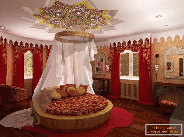 En el centro de la composición hay una cama redonda debajo del dosel. La atención atrae al techo, que está decorado de manera interesante sobre la cama.