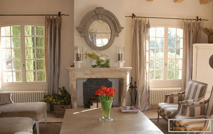 Sala de estar en el estilo del país con notas de romanticismo. Hermosas ventanas grandes y cómodos muebles para el hogar. Una gran idea para una gran familia.