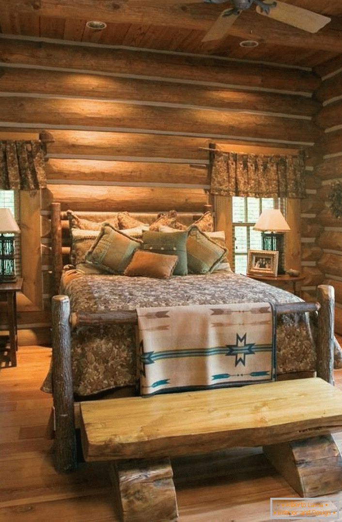 Un ejemplo clásico de un dormitorio en un estilo rústico. Cama interesante de una casa de troncos áspera y sin tratar. 