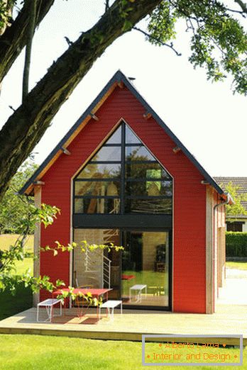Interior de una pequeña casa de madera con grandes ventanales