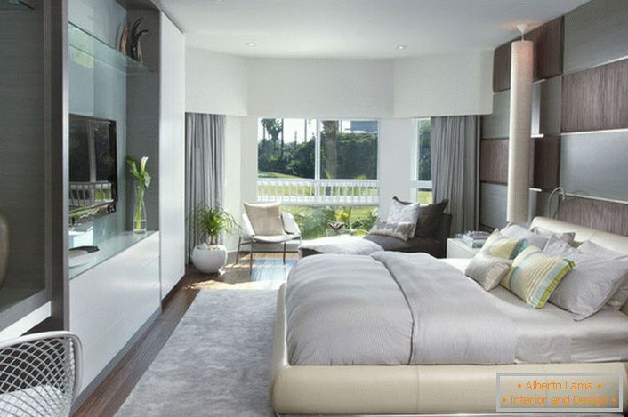 Cama suave a granel en el dormitorio con un estilo moderno. Los muebles con una superficie brillante se integran bien con la composición general del interior.