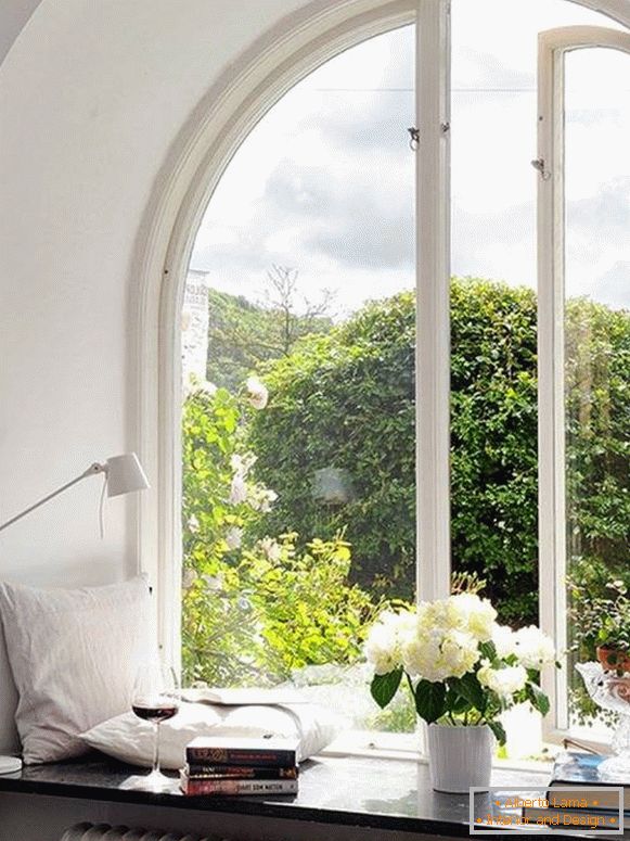 Decoración de ventana con almohadas, libros, flores