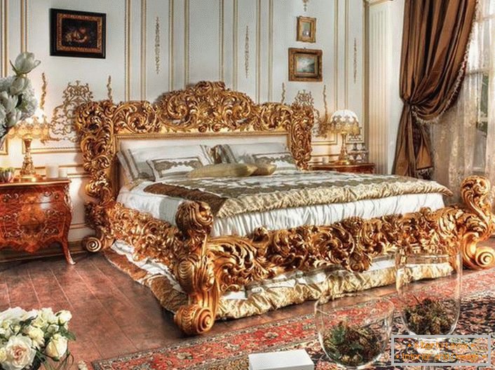 Una cama de lujo está hecha con las mejores tradiciones del estilo Imperio. Enormes espaldas de una cama de madera tallada de noble color dorado se destacan contra el fondo de otros detalles interiores.