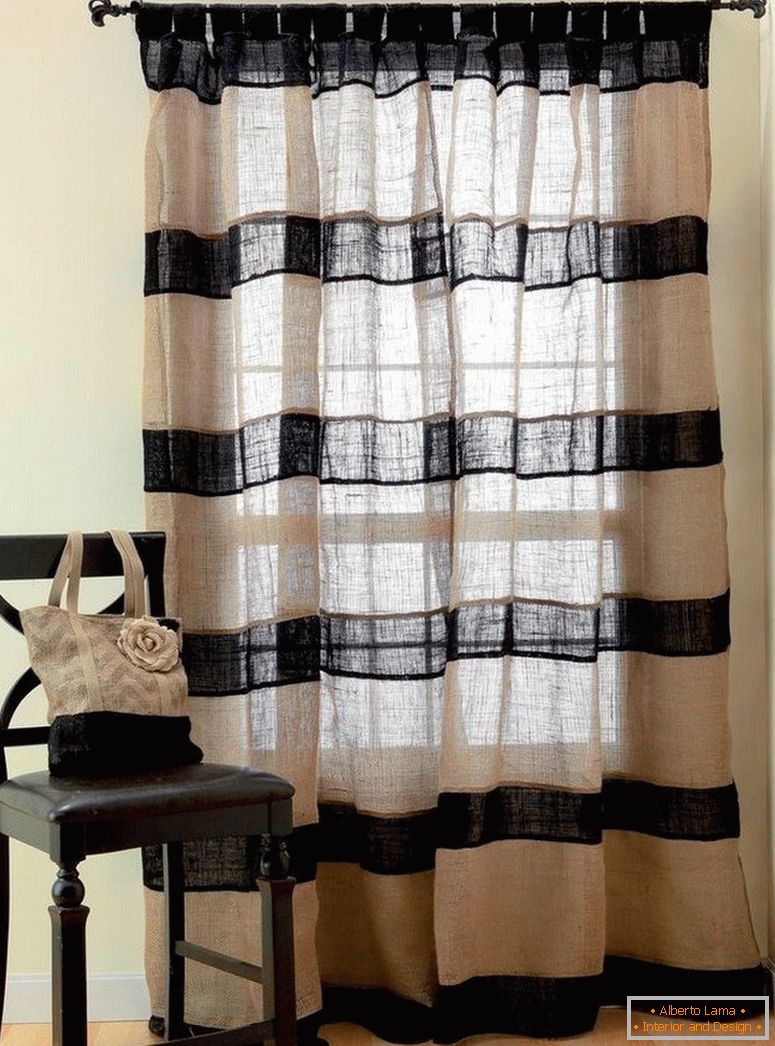 Una silla junto a la ventana con cortinas de tela de saco