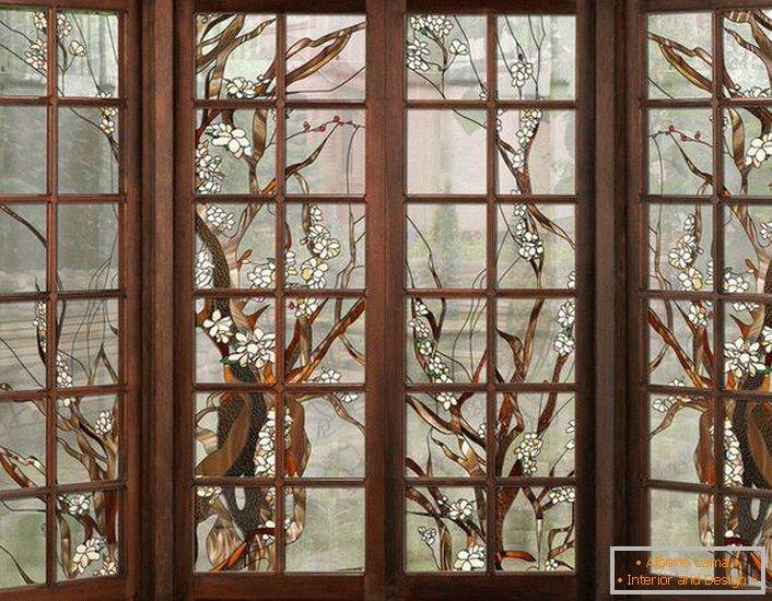 Las ventanas en el marco de madera oscura están decoradas con vidrieras. Figura sin complicaciones adecuada para el diseño de interiores en el estilo de país o moderno.