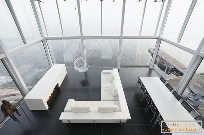 Diseño lacónico de la sala de estar en un estilo minimalista. Un mueble interesante es una silla suspendida de un techo alto.