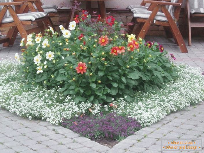 En el patio de la casa hay un área de recreación. Un elemento interesante de la composición del paisaje es el jardín de flores modular.