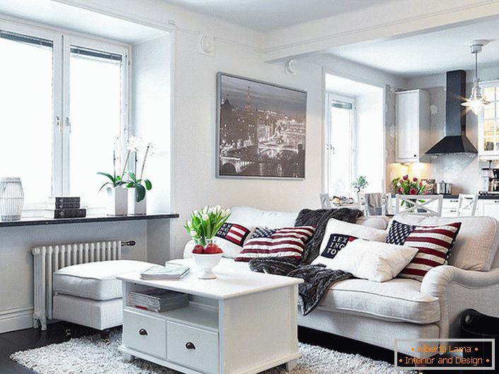 Un acogedor apartamento tipo estudio en estilo escandinavo está decorado principalmente en blanco. Las ventanas sin cortinas permiten que entre suficiente luz natural a la habitación.