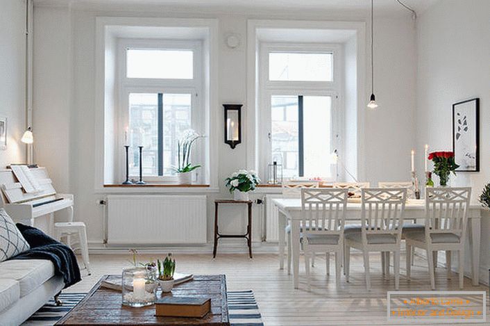 La elegante sala de estar se divide en una zona de estar y un comedor. De acuerdo con el estilo escandinavo, las paredes de la habitación están decoradas en blanco.