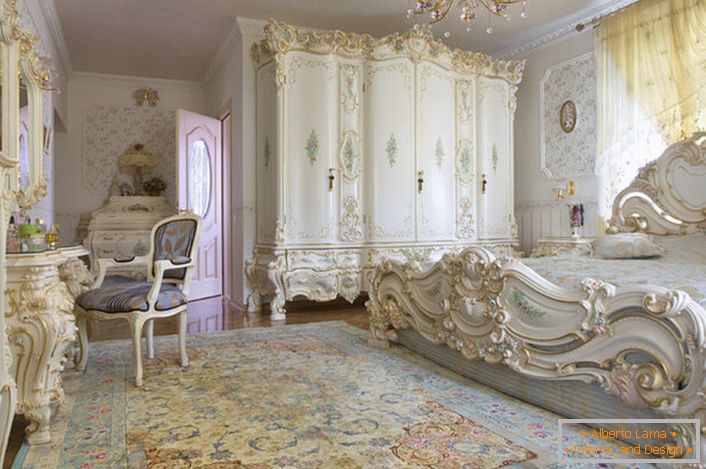Dormitorio blanco como la nieve con muebles tallados en madera maciza. La cama con un cabecero alto en la cabecera, encaja elegantemente en el interior en el estilo barroco.