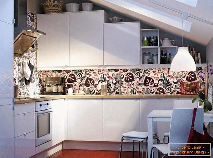 Los modernos electrodomésticos incorporados se integran armoniosamente en el diseño general de la cocina. El diseño lacónico de un espacio pequeño en el piso del ático está diseñado en estricta conformidad con los requisitos del estilo escandinavo.