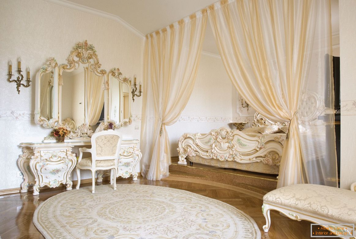 Los espejos de marco y los elementos decorativos de los muebles están hechos en un estilo con el uso de oro. Para ahorrar espacio, la cama está escondida en un nicho enmarcado por cortinas.