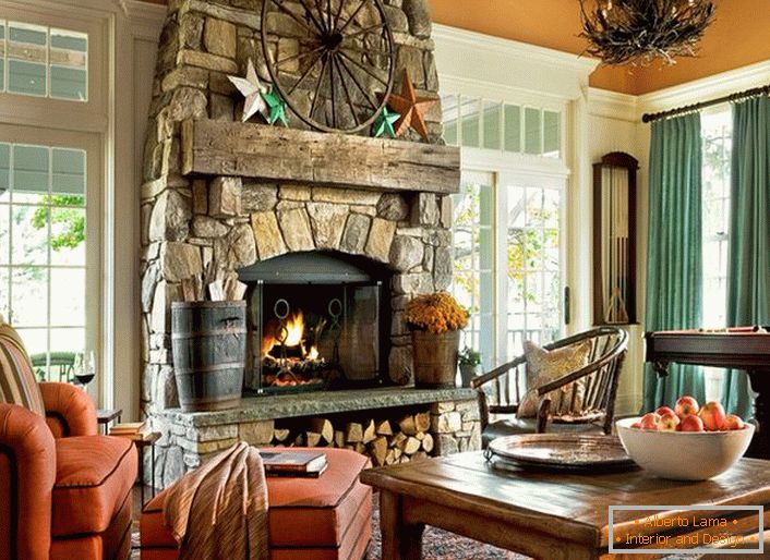 Una espaciosa habitación de huéspedes en una casa de campo en estilo rústico. Cabe destacar las grandes ventanas con marcos de madera y una gran chimenea, hecha con piedra natural.