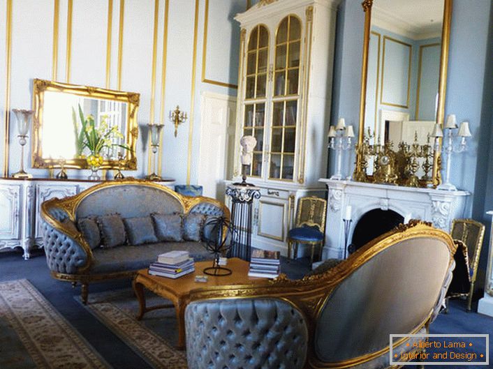 La sala de estar del estilo Imperio está hecha en suaves colores azules, que se combinan armoniosamente con los elementos dorados de la decoración. Los espejos de marco y los elementos de muebles tallados están hechos en un estilo unificado.