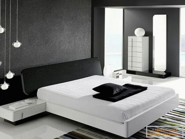 La pared en la cabecera de la cama, decorada con una inserción gris mate, de acuerdo con el estilo de alta tecnología, está en armonía con el piso blanco brillante.