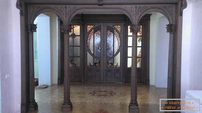 Las puertas de entrada al estilo Art Nouveau están hechas de maderas oscuras de madera costosa. El pasillo completo con tales puertas parece solemne y pomposo. 
