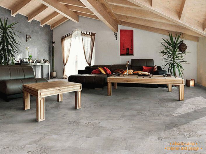 La cubierta de pisos y paredes imita un acabado áspero. Los techos de madera se combinan en una composición común con muebles. Una variación de la suerte del estilo loft en la sala de estar.