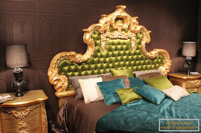 Una alta espalda adornada en la cabecera de la cama está cubierta de seda de olivo. Interesantes almohadas de colores contrastantes y colchas en la cama.