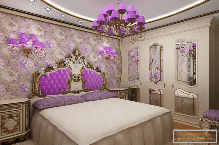 Elegante dormitorio barroco con un acento interesante en la iluminación. Lámparas de araña y de noche con los mismos tonos violetas combinados armónicamente con la tapicería del respaldo en la cabecera de la cama.