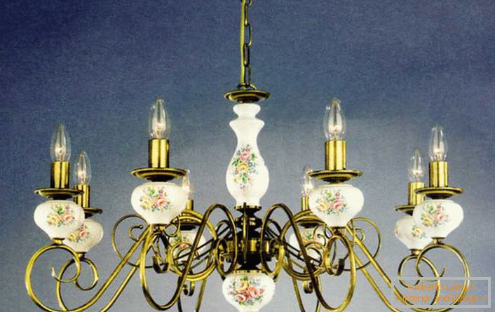 La araña con velas de imitación está decorada con motivos florales de acuerdo con los requisitos del estilo rural.