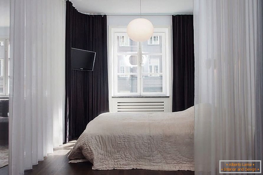 Una cama con una cortina en un apartamento de una habitación de 36 metros cuadrados