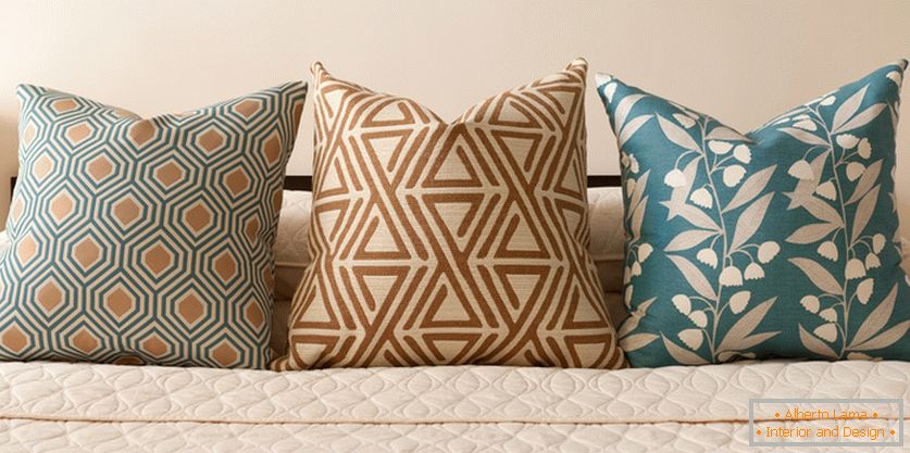 Almohadas decorativas en la cama en tonos pastel-turquesa