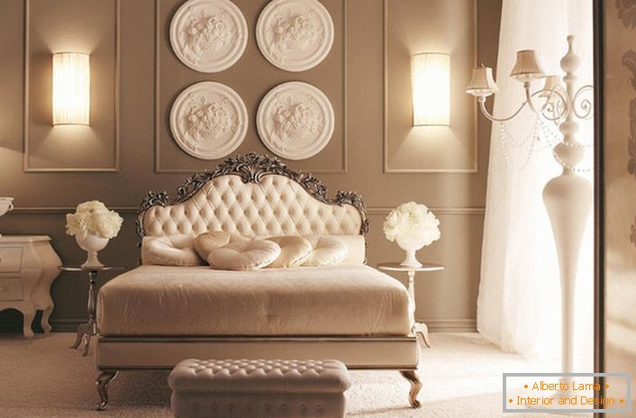 En la cabecera de la cama, la pared está decorada con una composición de estuco de diseño. Exquisita decoración de dormitorio en el estilo Art Deco.