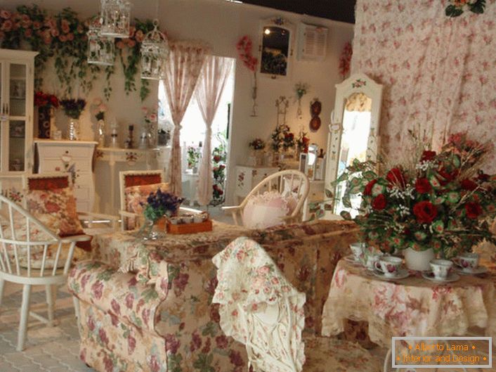 Flores en el jarrón, en la pared e incluso en la tapicería del sofá. Pasillo en el estilo de Provence en una pequeña casa de campo en el sur de Francia.