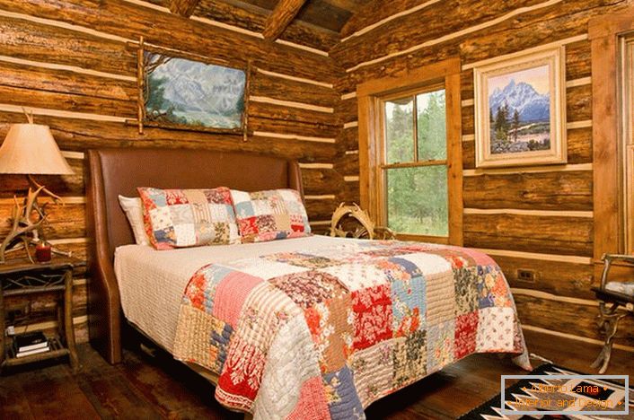 Un dormitorio en un estilo rústico en un pabellón de caza. Destaca la decoración de las paredes con la ayuda de una cabaña de troncos. 