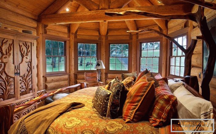 Uno de los dormitorios de la casa cerca del lago está hecho al estilo de un país rural. Decoración de madera Muebles masivos y elementos de decoración son seleccionados en las mejores tradiciones de estilo.