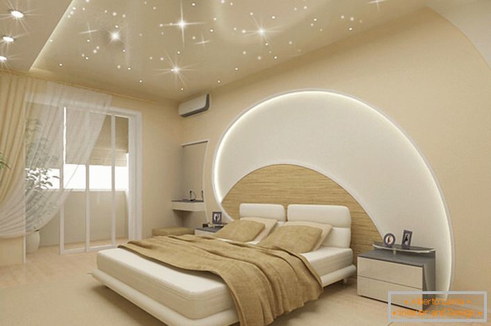La atención atrae la decoración de paredes y techo en el dormitorio en un estilo moderno. Rayas LED atraviesan el techo y la pared sobre la cama, los techos tensados ​​imitan el cielo mágico estrellado.
