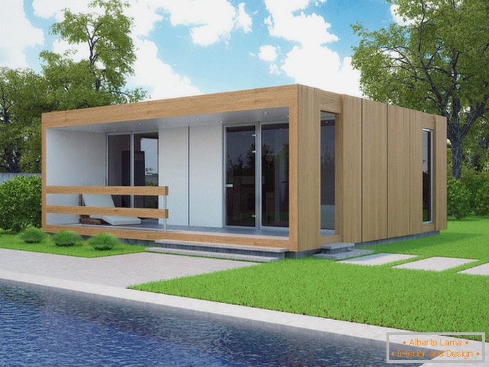 Una pequeña casa modular con una piscina en el patio. El diseño elegante de una casa que se está construyendo rápidamente se ve orgánicamente contra el fondo de un césped corto y corto.