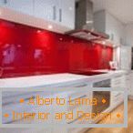 Muebles blancos y un delantal rojo en el interior de la cocina