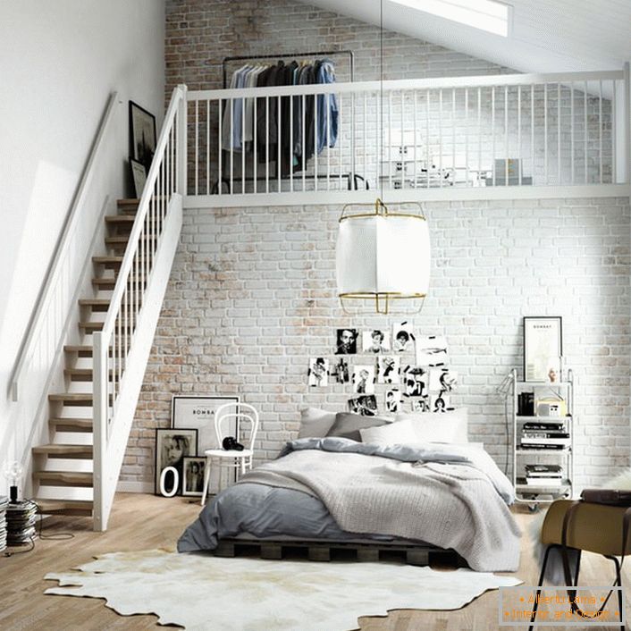 El dormitorio en el estilo escandinavo se divide funcionalmente en dos zonas. Una escalera de madera conduce al segundo piso, donde hay un pequeño vestidor en la cama.