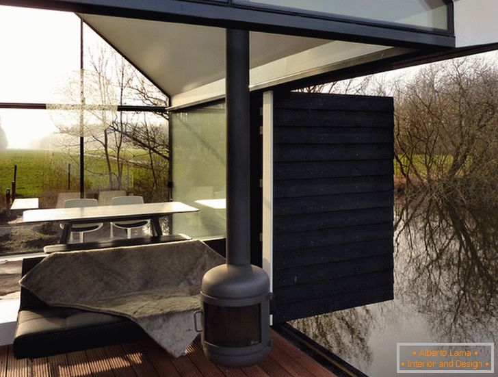 Terraza de una pequeña casa de cristal junto al lago en Holanda