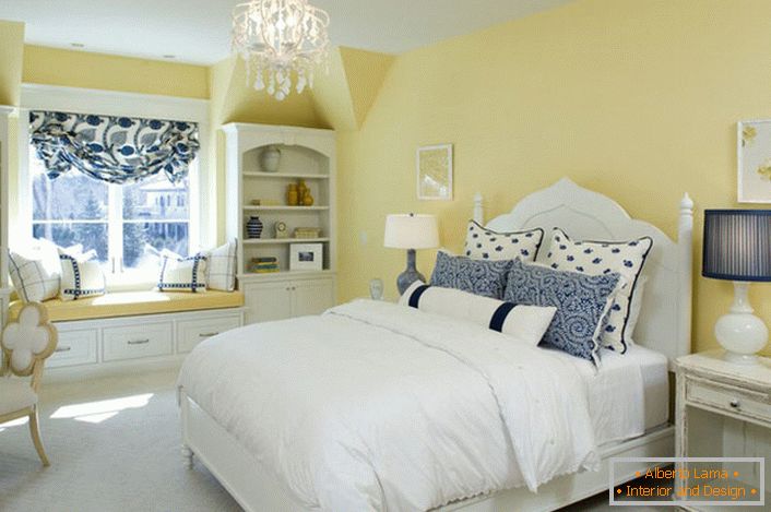 El color amarillo desteñido del acabado armoniza con los elementos blancos y azules de la decoración. Una combinación inusual es una solución audaz para un dormitorio en estilo rústico.