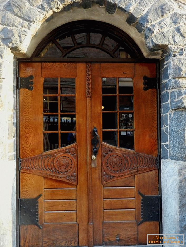 Las puertas en estilo Art Nouveau decoran la puerta de entrada de una casa rural con una fachada de piedra natural. 