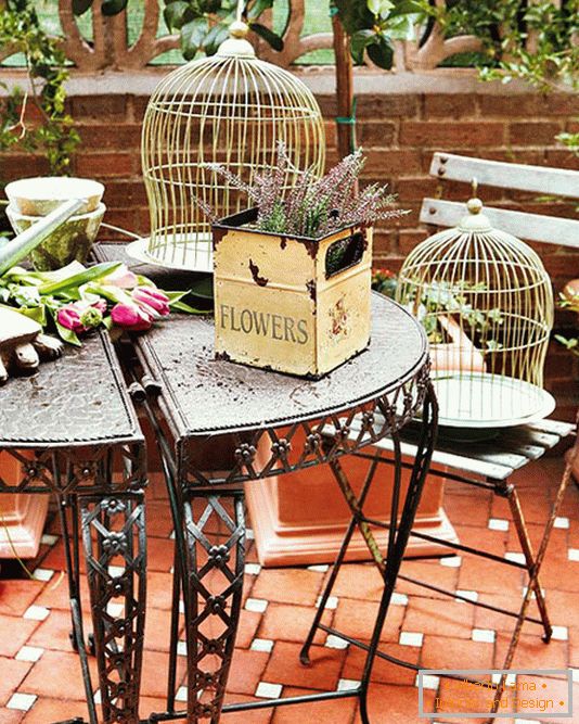 Mesa forjada, cajas con flores y jaulas para pájaros