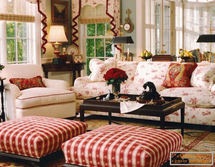 Una sala de estar simple, modesta y acogedora en estilo inglés en una pequeña casa de campo. Los toques de rojo hacen que la atmósfera de la habitación sea relajada y alegre.