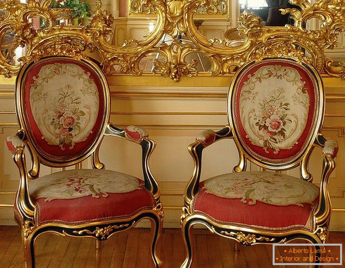 Estuco a cielo abierto de color dorado en el espejo y sillas con tapicería suave de color rojo: brillantes representantes del estilo barroco.