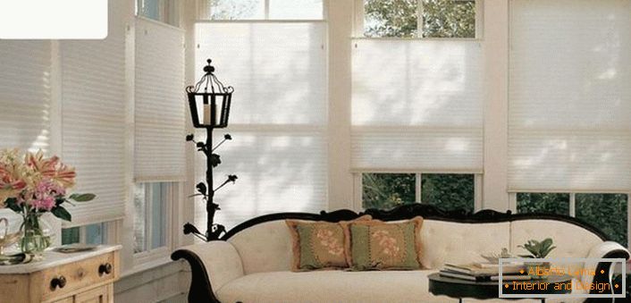 Modernas cortinas de aire de un solo color, plisadas, no sobrecargan el ambiente refinado de la sala de estar de una antigua casa de campo. 