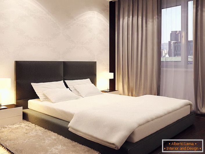 La cama en el estilo minimalista se asemeja a un podio bajo. La cabecera alta y suave hace que el diseño sea más suave y suave.
