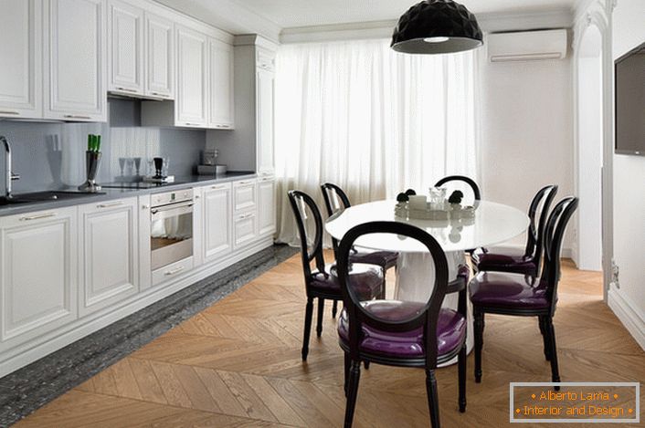 Cocina interior blanca con toques de gris oscuro en estilo ecléctico. Sillas interesantes con espaldas transparentes y tapicería suave de color púrpura.
